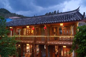 A traditional building with a tiled roof, wooden balconies, and red lanterns. - Xiangshangpin Hostel (Lijiang)