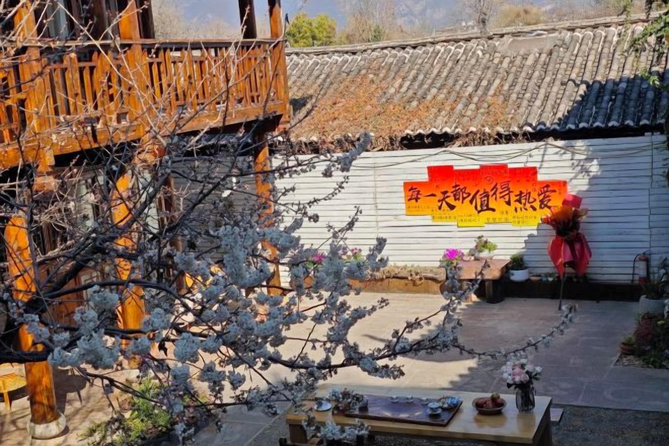 Une cour traditionnelle chinoise, dotée d’un balcon en bois, d’un toit recouvert de tuiles et d’une enseigne portant des caractères chinois.