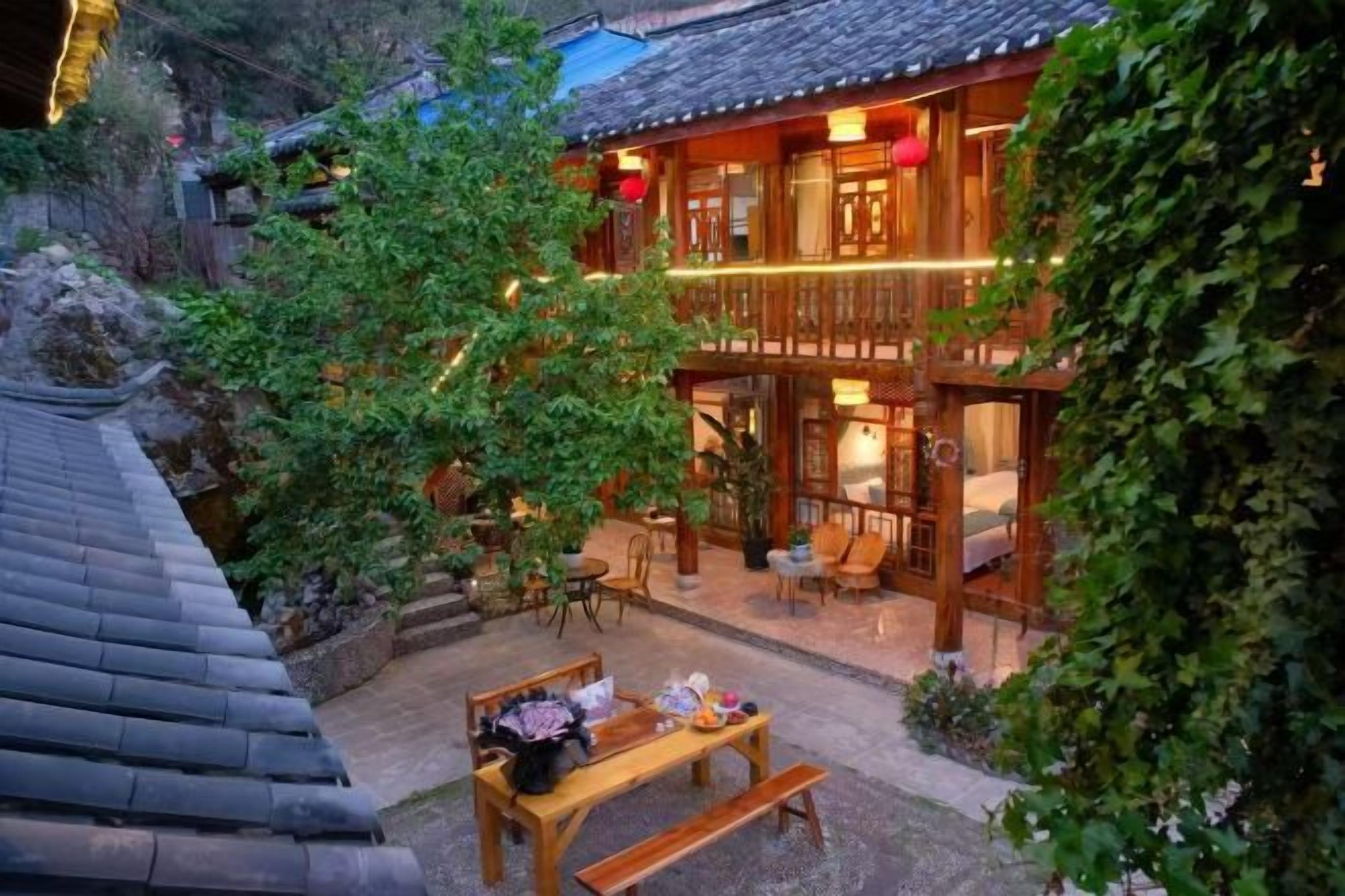 A traditional wooden building with a balcony, outdoor seating, and a garden area.