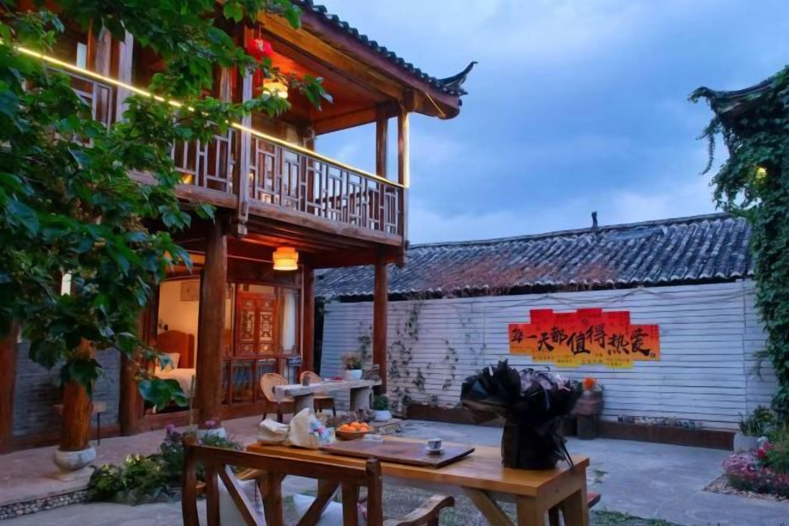 A traditional wooden building with a balcony, a dining table set outdoors, and a sign with red characters.