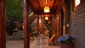Un espace extérieur abrité, doté de poutres en bois, d’un sol en pierre et de plantes en pot.