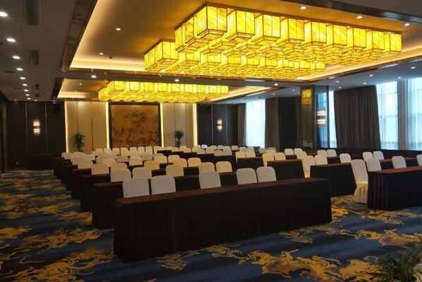 A conference room with rows of chairs, a large chandelier, and a carpeted floor. - Shizhushan dezheng Hotel (Yizheng)