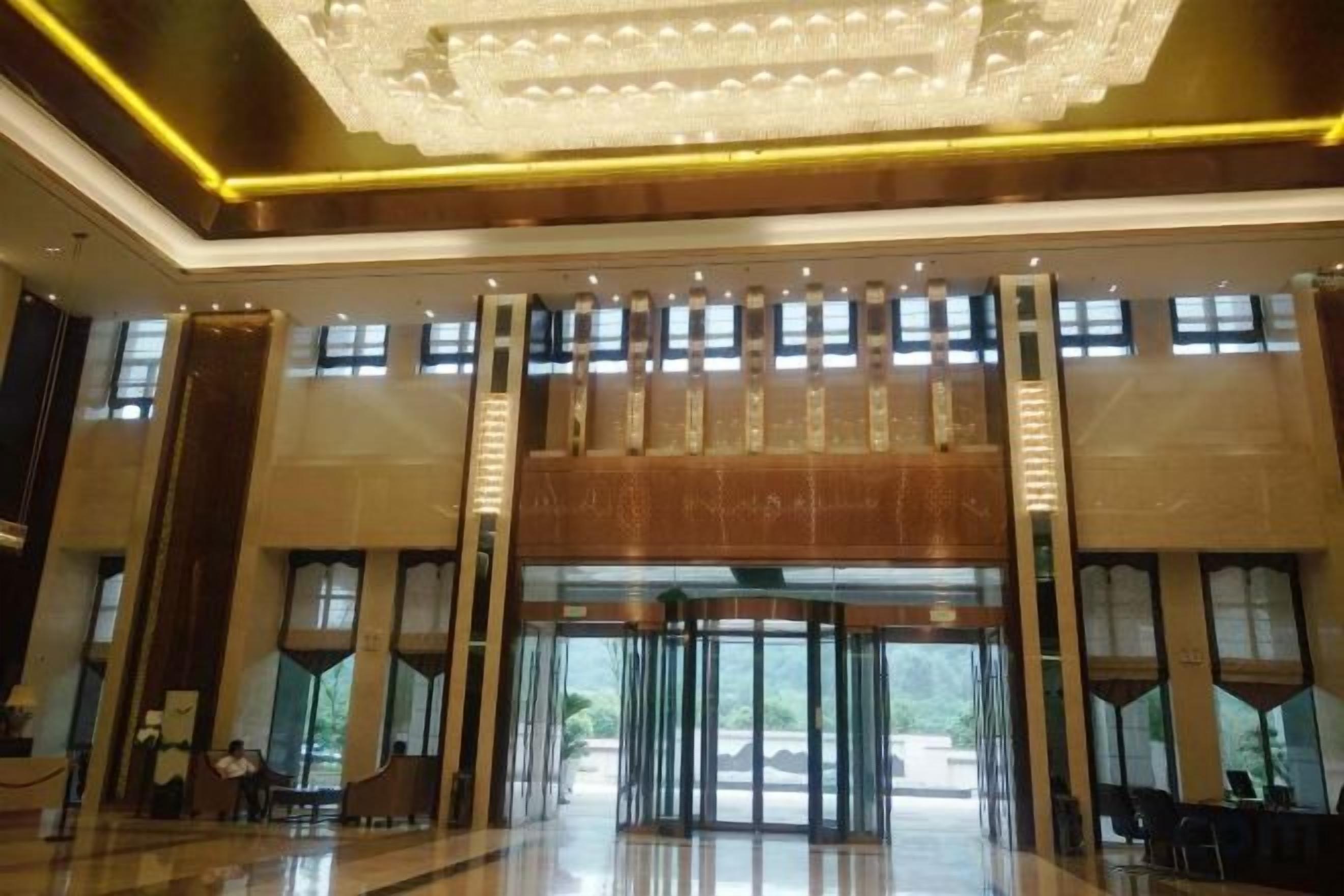 Un vestíbulo amplio con techo alto, ventanas grandes y una escalera central.