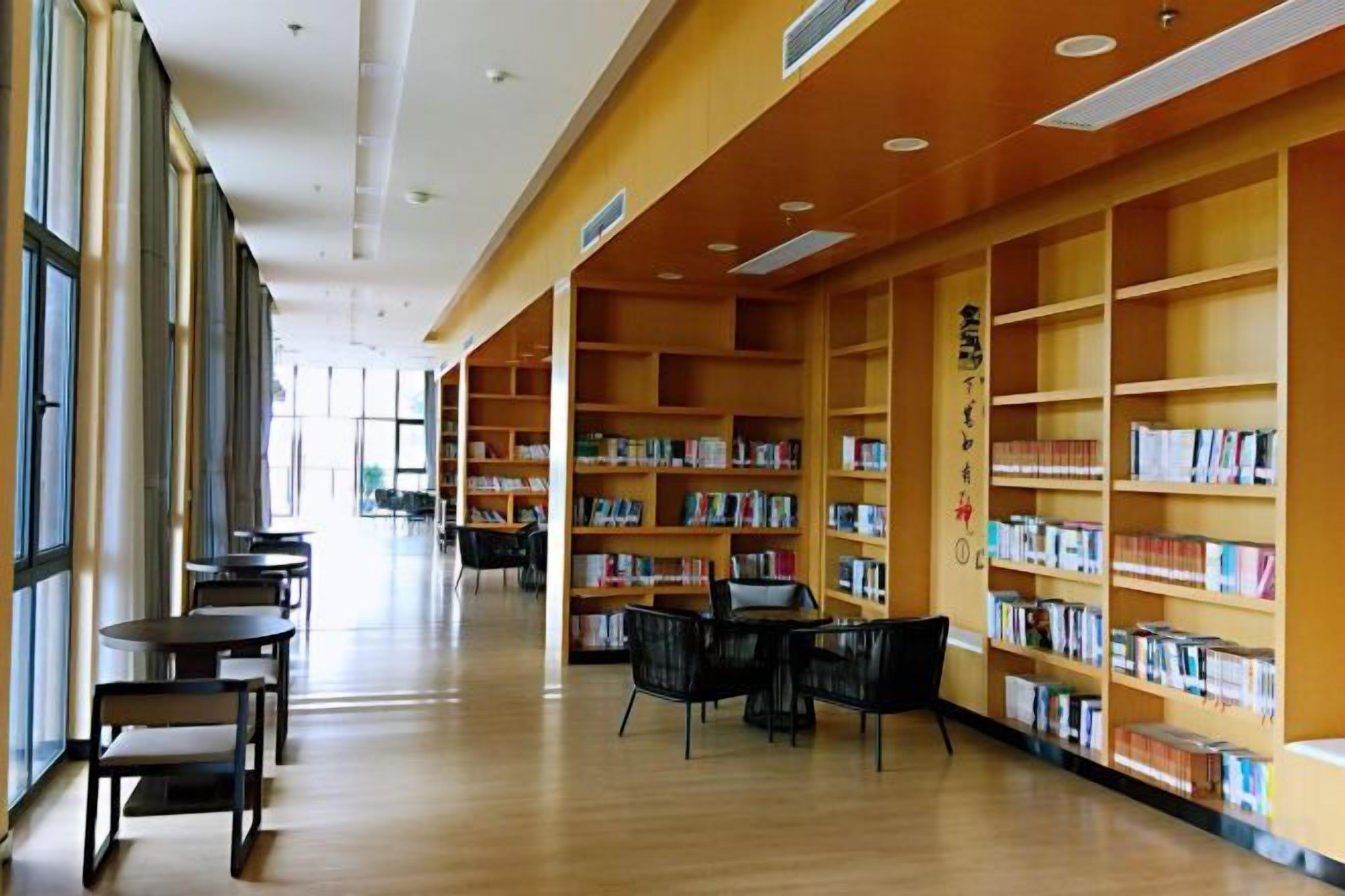A library interior with bookshelves, tables, and chairs.