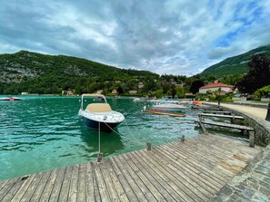 A wooden dock extending into a lake with boats moored nearby. - Reflet Bleu By the Lake 3* (Doussard)