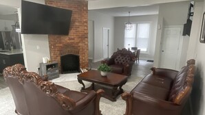 Ein Wohnzimmer mit Kamin, Ledersofas, einem Couchtisch und einem flachbildfernseher an der Wand.