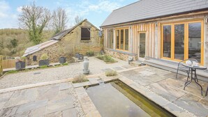 A stone building with a sloped roof and a wooden structure with large windows. - 3 bedroom accommodation in Rackenford, near Tiverton (Rackenford, near Tiverton)