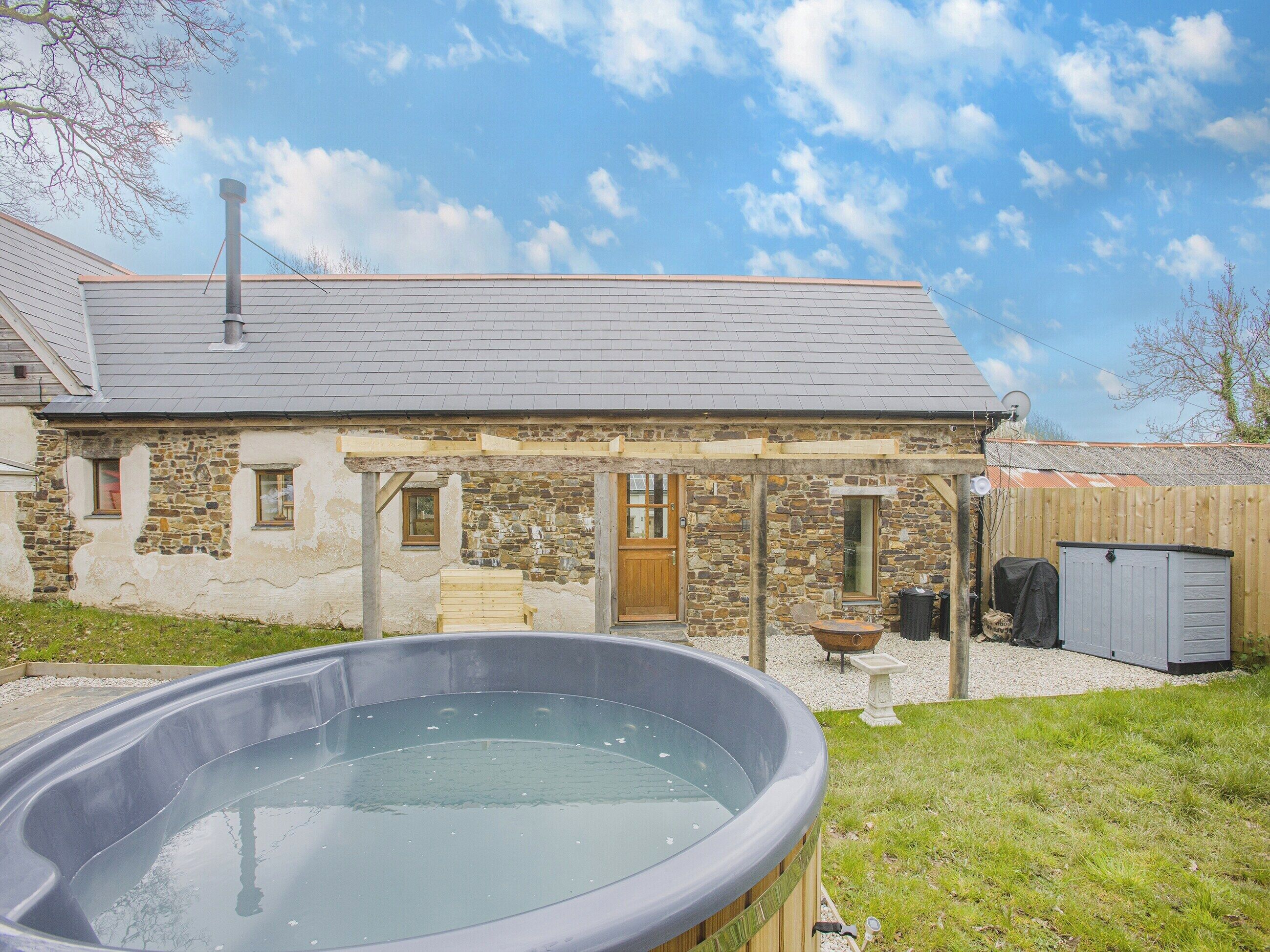 A stone house with a hot tub in the foreground.