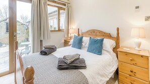 A bedroom with a bed, bedside tables, a lamp, a window with curtains, and a view of the outside. - 3 bedroom accommodation in Rackenford, near Tiverton (Rackenford, near Tiverton)