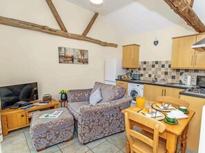 A compact living space with a sofa, ottoman, television, kitchenette, and a dining area with a table set for two.