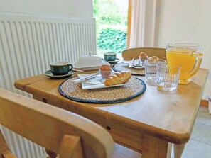 A wooden table with breakfast items including bread, eggs, and a jug of orange juice. - 1 bedroom accommodation in Catfield (Catfield)