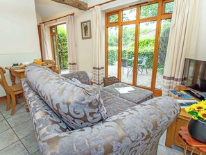 Ein gemütliches Wohnzimmer mit einer Couch, einem Fernseher und einem Essbereich mit Stühlen und einem Tisch.