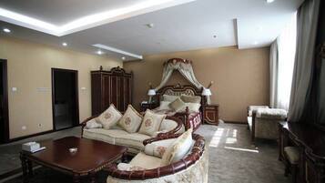 A spacious bedroom with a large bed, a sofa, a wooden coffee table, and a wardrobe.
