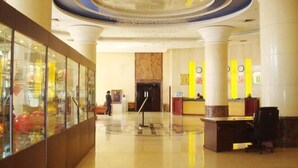 A spacious lobby with a reception desk, a glass display case, and a polished floor.