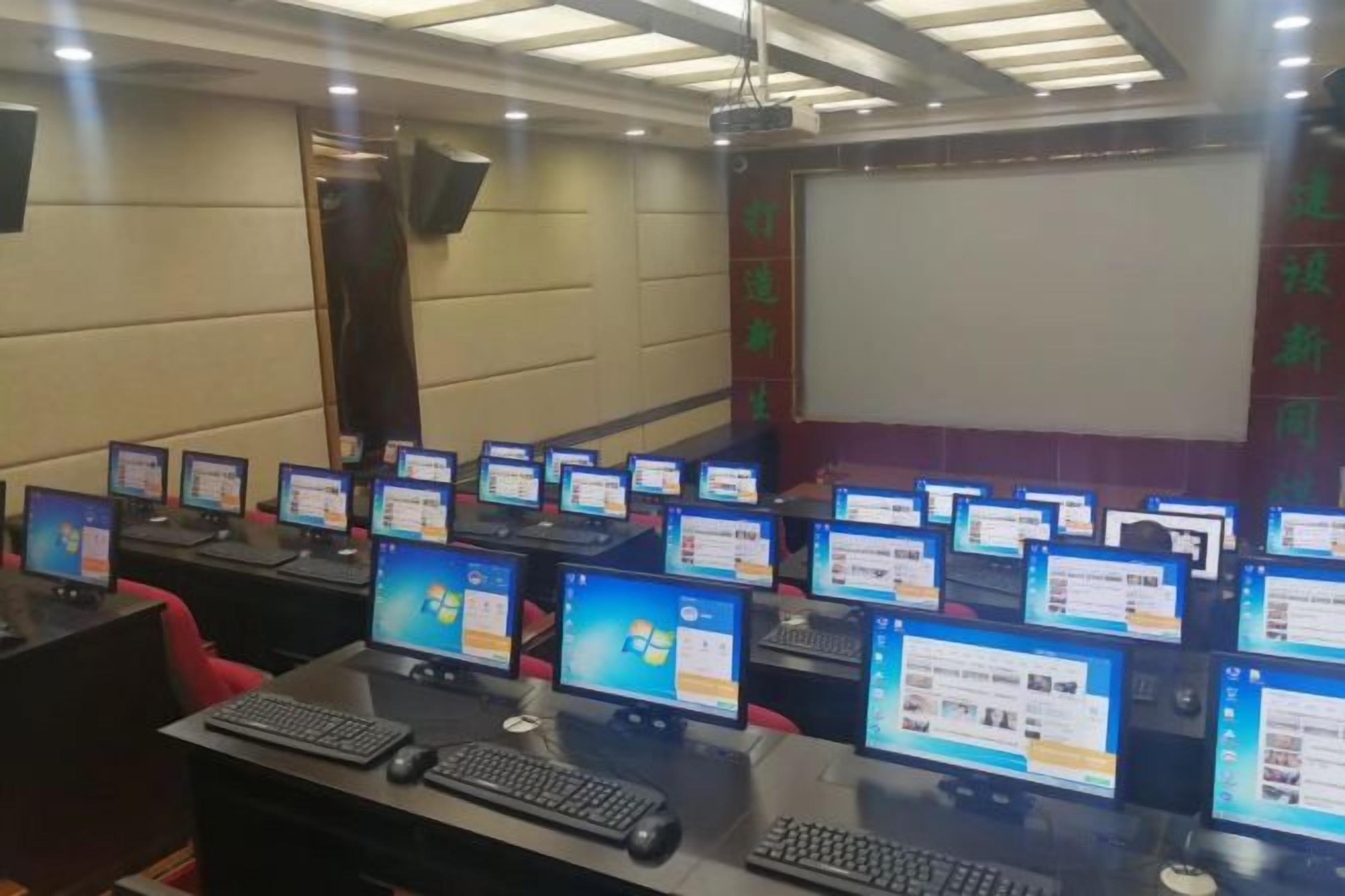 A conference room with multiple computer stations, each with a monitor, keyboard, and mouse.