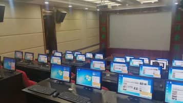 A conference room with multiple computer stations, each with a monitor, keyboard, and mouse.