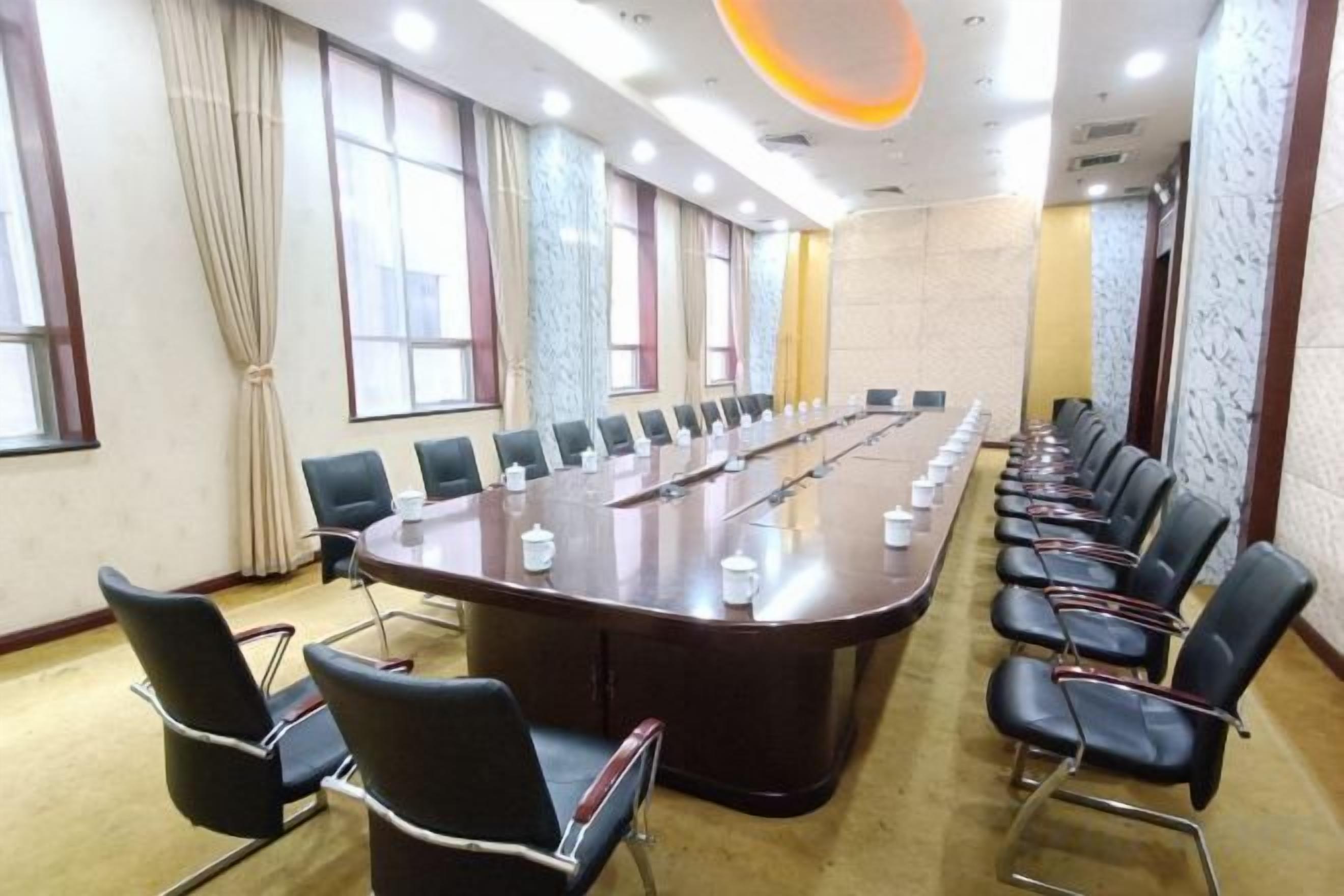 Uma sala de conferências com uma mesa comprida, cadeiras e piso coberto de carpete.