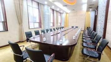 Uma sala de conferências com uma mesa comprida, cadeiras e piso coberto de carpete.