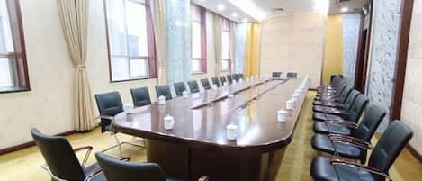 A conference room with a long table, chairs, and a carpeted floor.