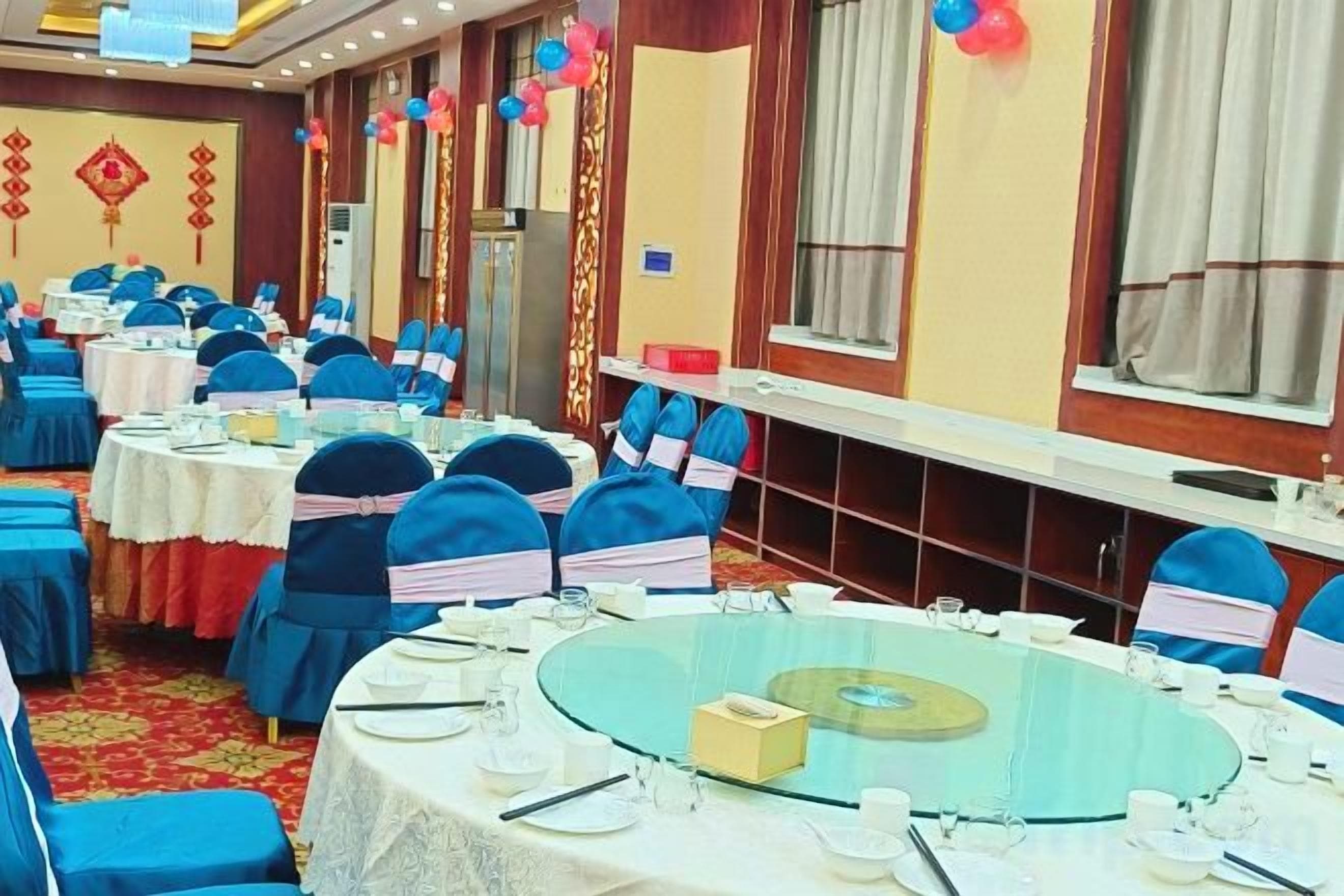 Un salón de banquetes con mesas redondas, sillas y alfombra roja.
