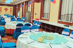 Un salón de banquetes con mesas redondas, sillas y alfombra roja.