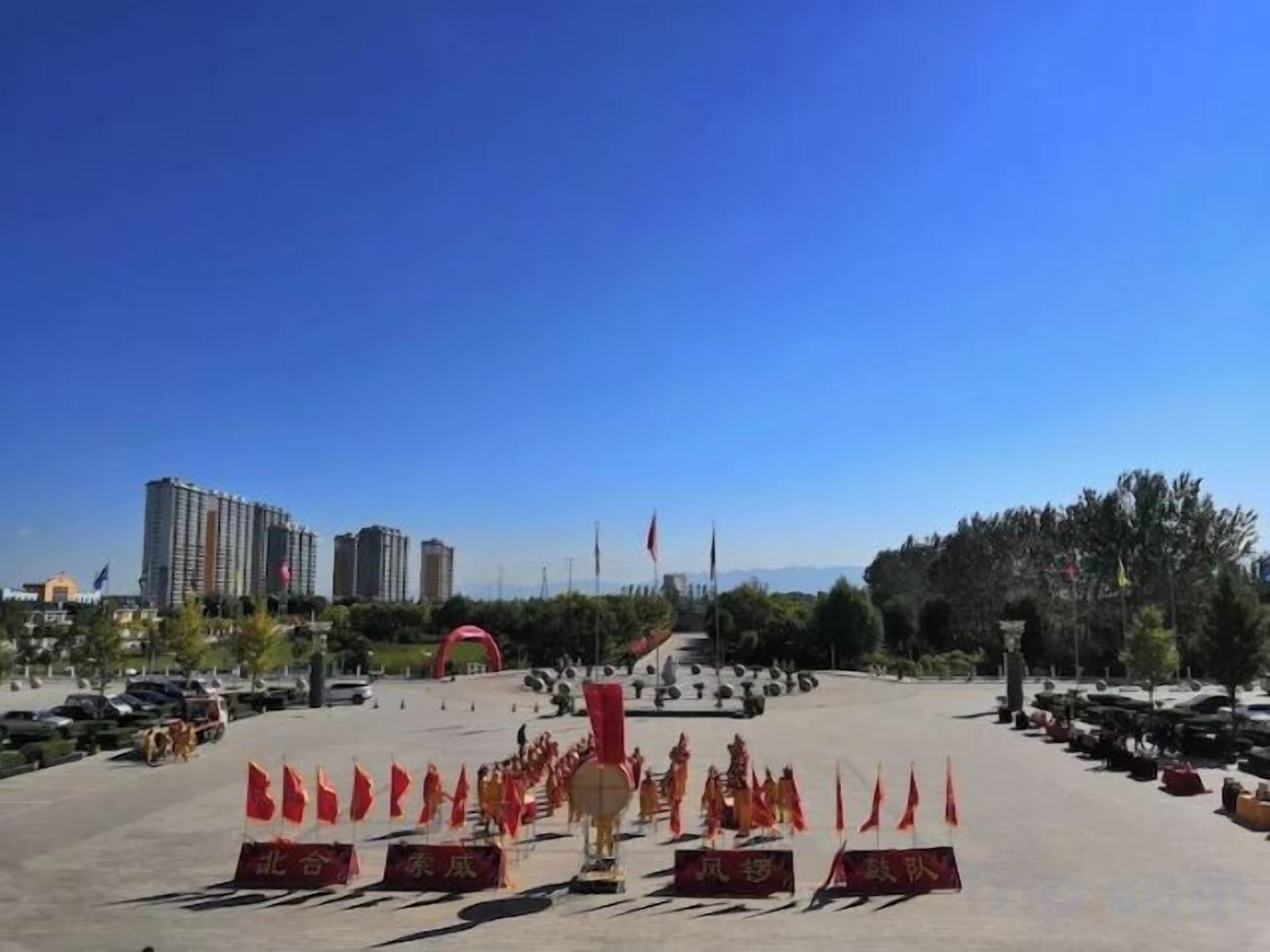 A large open plaza with a clear sky, surrounded by buildings and trees.