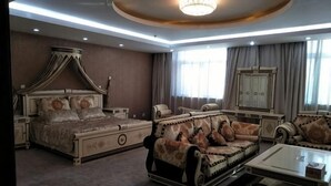 A bedroom with a four-poster bed, a sofa, a coffee table, and a nightstand.