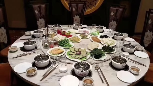 A round dining table with various dishes, bowls, and utensils.