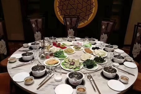 A round dining table with various dishes, bowls, and utensils.. Xinzhou Conference Hotel