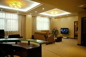 A hotel room with a glass dining table, a sofa, a TV, and a ceiling light fixture. - Xinzhou Conference Hotel (Xinzhou)