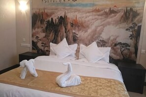 A bed with white bedding, a decorative wall painting, and two towels shaped like swans. - Xinzhou Conference Hotel (Xinzhou)