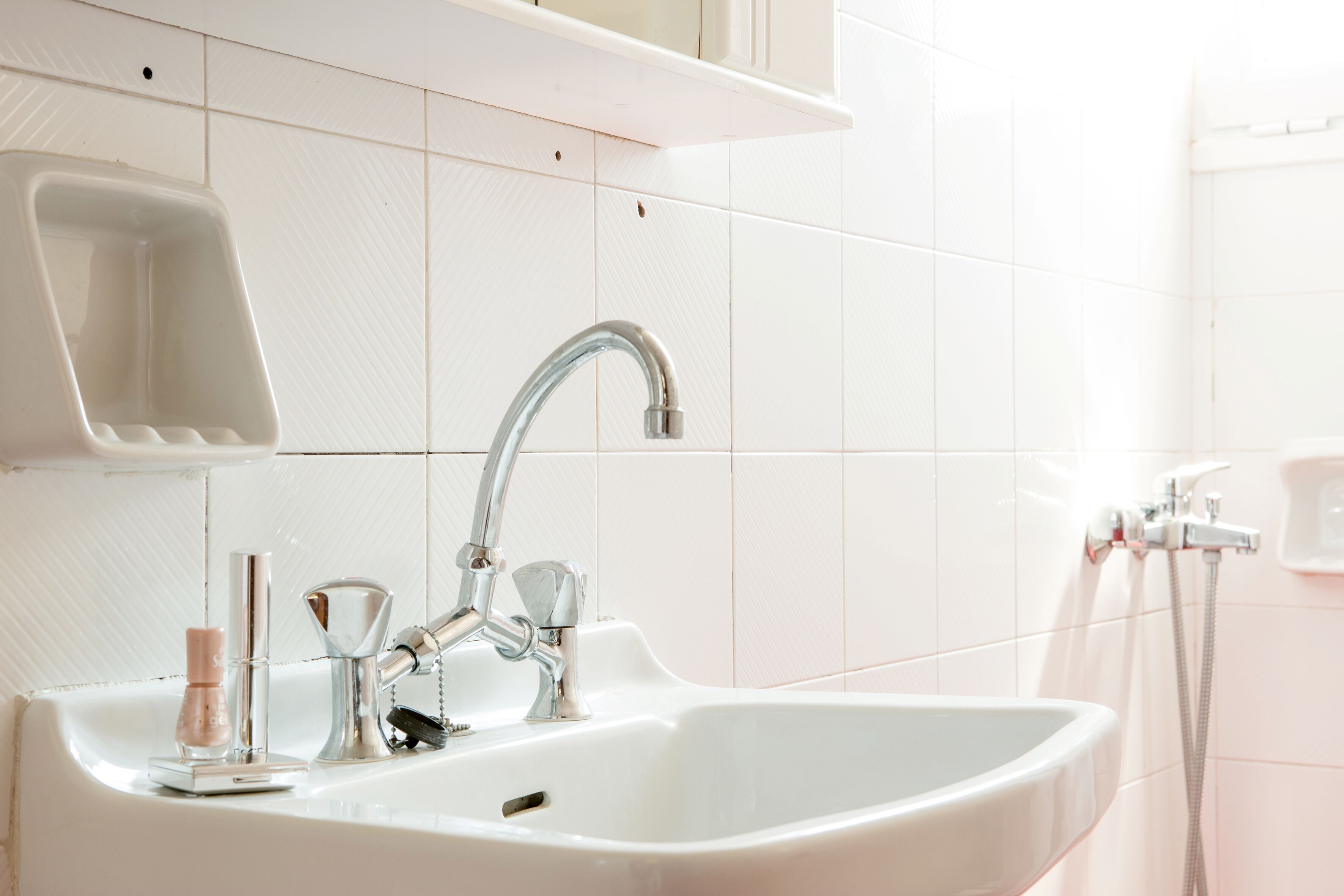 A bathroom with a white sink, chrome faucet, and a handheld showerhead.