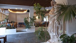 A spacious lobby with a statue, seating areas, and potted plants. - Albatross Hotel (Platanias)