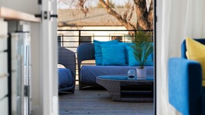 An open doorway leading to a deck area with a sofa and a potted plant. - Cozy Deck • Fire Pit • EV Charger • Outdoor Dining (Austin)