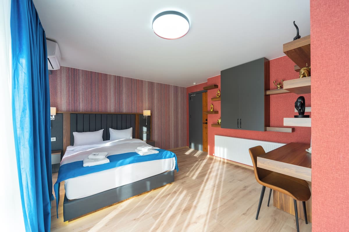 A modern hotel room with a bed, a desk, and a chair.
