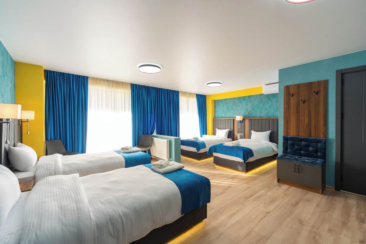 A hotel room with two beds, a desk, a chair, a wardrobe, and a TV.