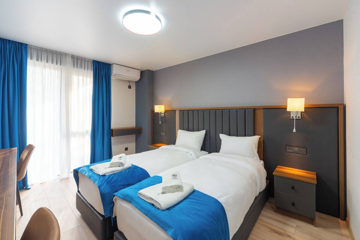A hotel room with two beds, a desk, and a chair.