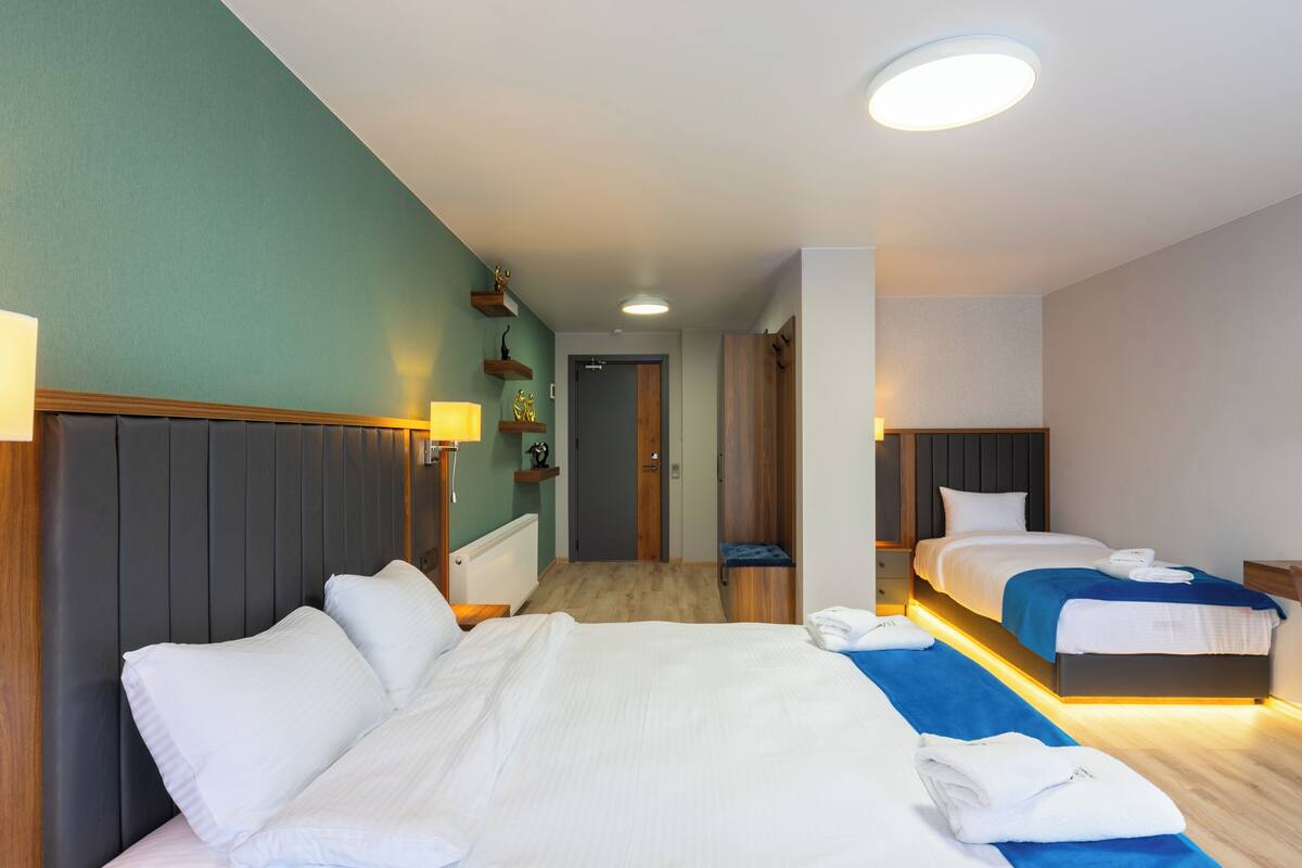 A hotel room with two beds, a wooden headboard, a small desk, and a nightstand.