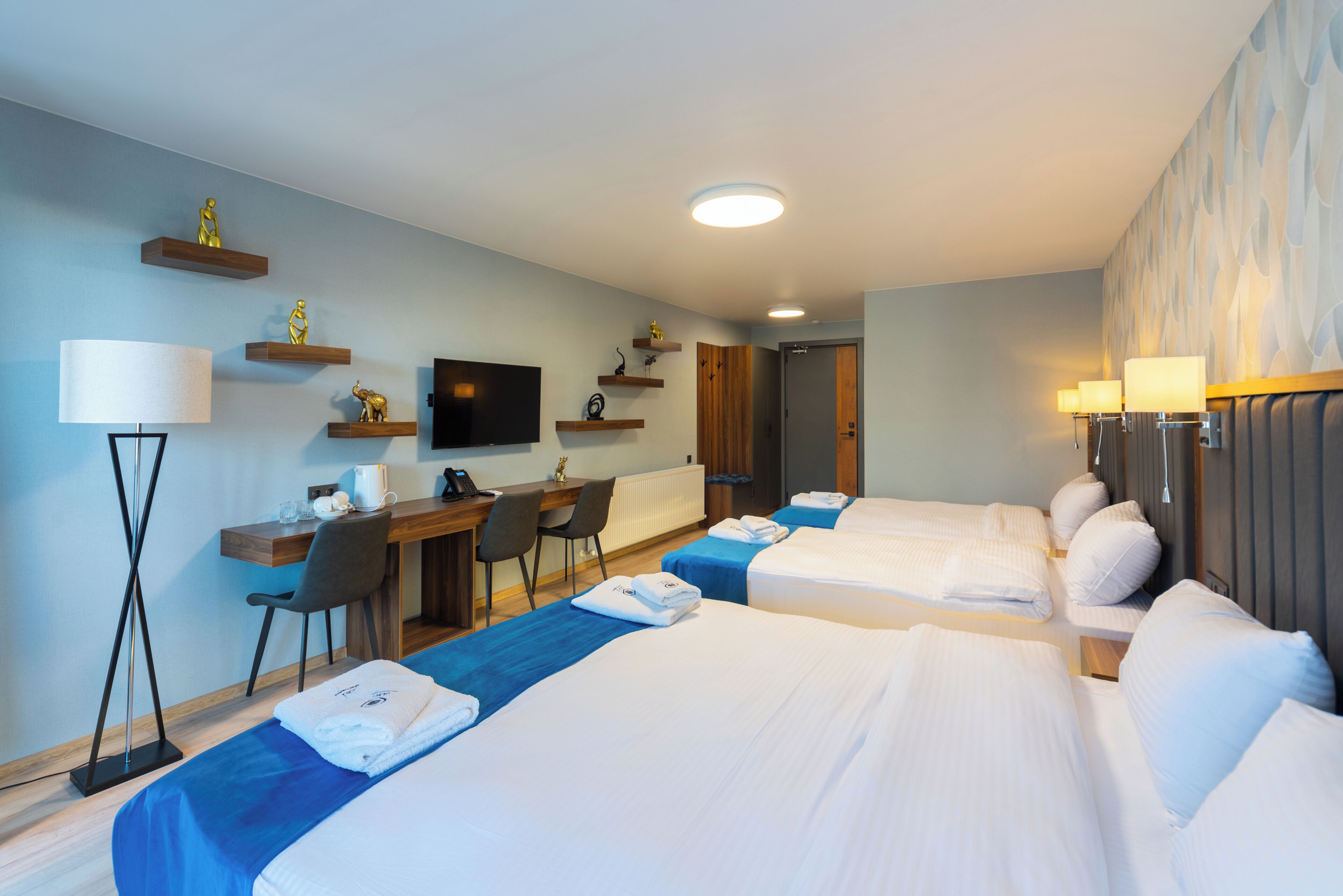 A hotel room with two beds, a desk, a chair, a television, and a bathroom door.