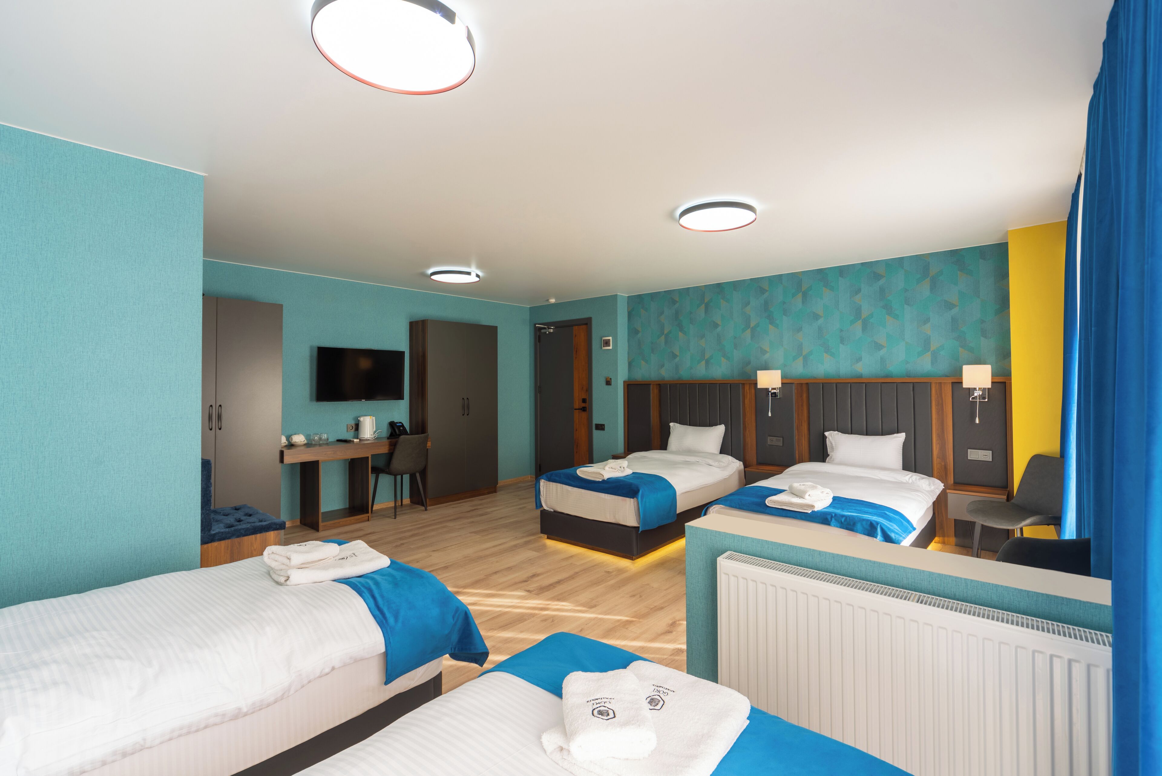A hotel room with two beds, a desk, a television, and a bathroom.
