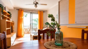 Ein Essbereich mit einem Holztisch, Stühlen, einem Deckenventilator und Blick durch eine Glastür in einen Außenbereich.