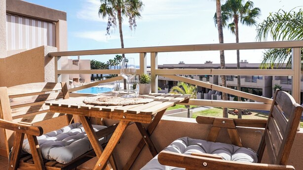 Eine Holzdielen-Terrasse mit Billardtisch, gepolsterten Stühlen und einem Glas Wein.