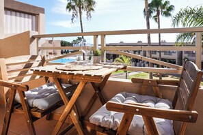 Eine Holzdielen-Terrasse mit Billardtisch, gepolsterten Stühlen und einem Glas Wein.