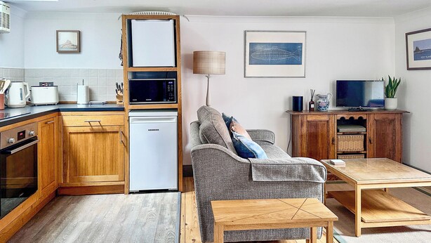 A compact living space with a kitchenette, a sofa, a television, and a dining area.