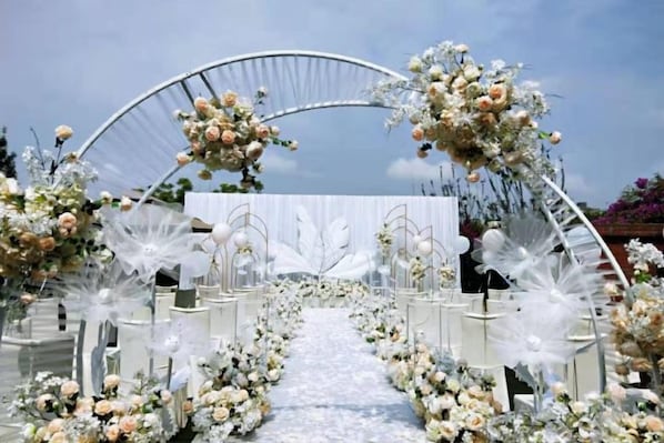An outdoor wedding aisle with floral decorations and white chairs. - Century Chanson Hotel (Mianyang)
