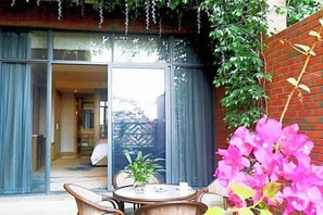 A room with a large sliding glass door leading to a balcony, a round table with chairs, and a potted plant. - Century Chanson Hotel (Mianyang)