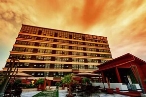 A multi-story hotel with a courtyard featuring outdoor seating and potted plants. - Century Chanson Hotel (Mianyang)
