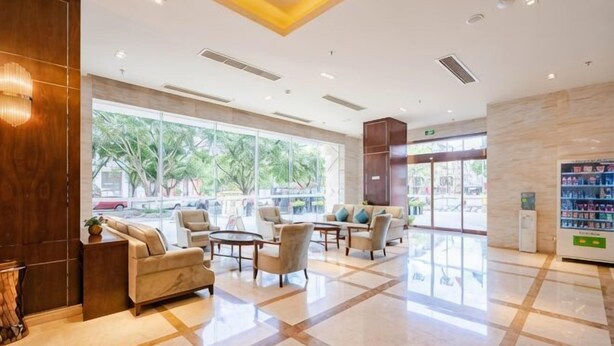 A hotel lobby with a large window, seating area, and a vending machine. - Century Chanson Hotel (Mianyang)