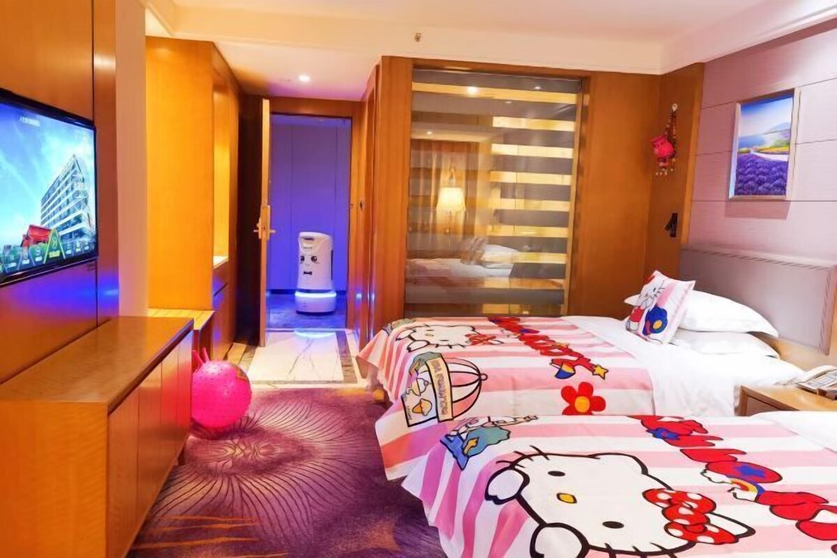 A hotel room with a bed, a TV, a bathroom, and a hallway.