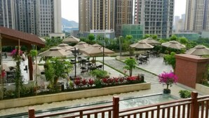 A rooftop terrace with outdoor seating, surrounded by high-rise buildings. - Century Chanson Hotel (Mianyang)